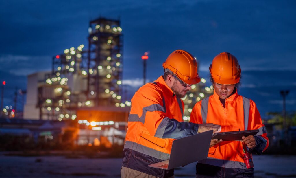 Two quality engineerings overlooking audit results while standing outside a refinery.