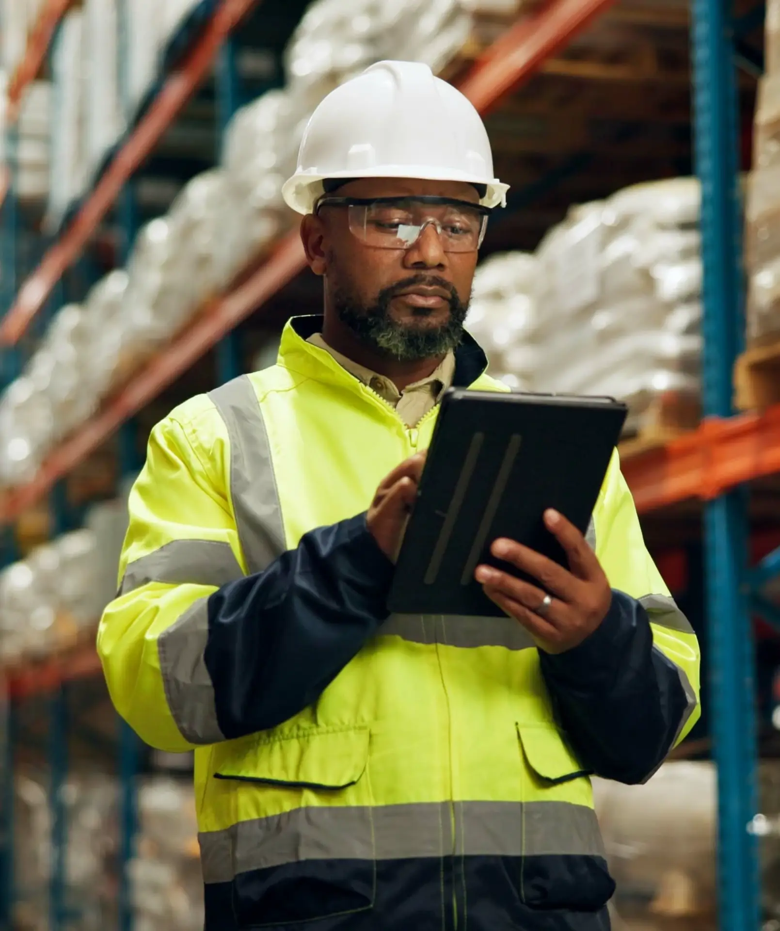 Person in safety gear using tablet to perform an audit.